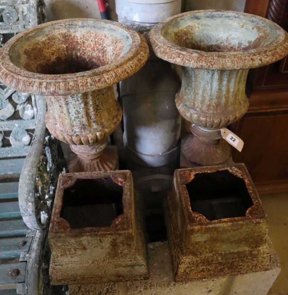A pair of Victorian style cast iron campana garden urns on stands, height 49cm